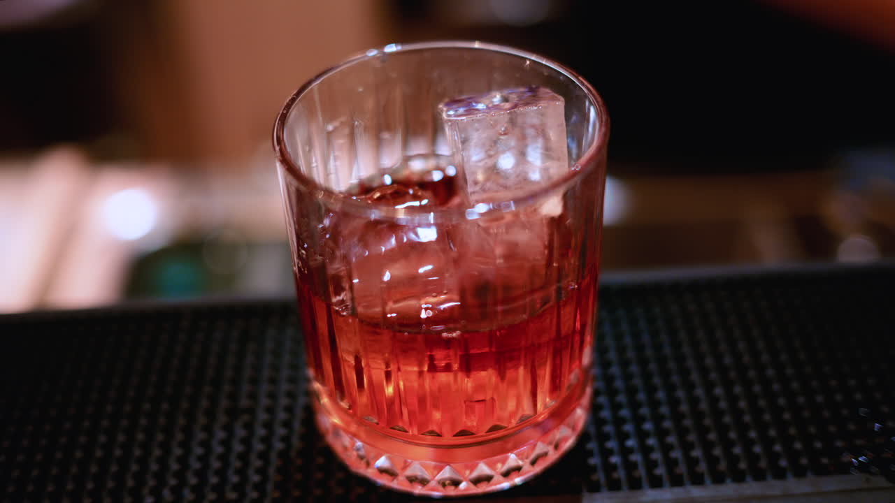 Primo piano dettagliato di un cocktail versato in un bicchiere con ghiaccio