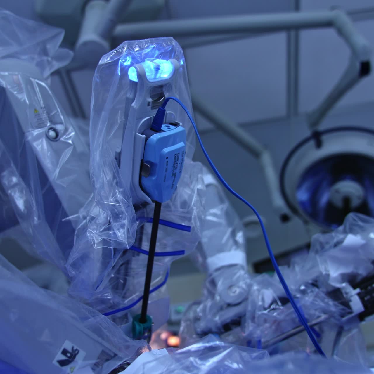 Slowly moving arms of Da Vinci robot coated in plastic. Surgeon robotic system operating the patient. Low angle view