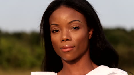 black woman standing in field during a warm summer day looking straight into camera