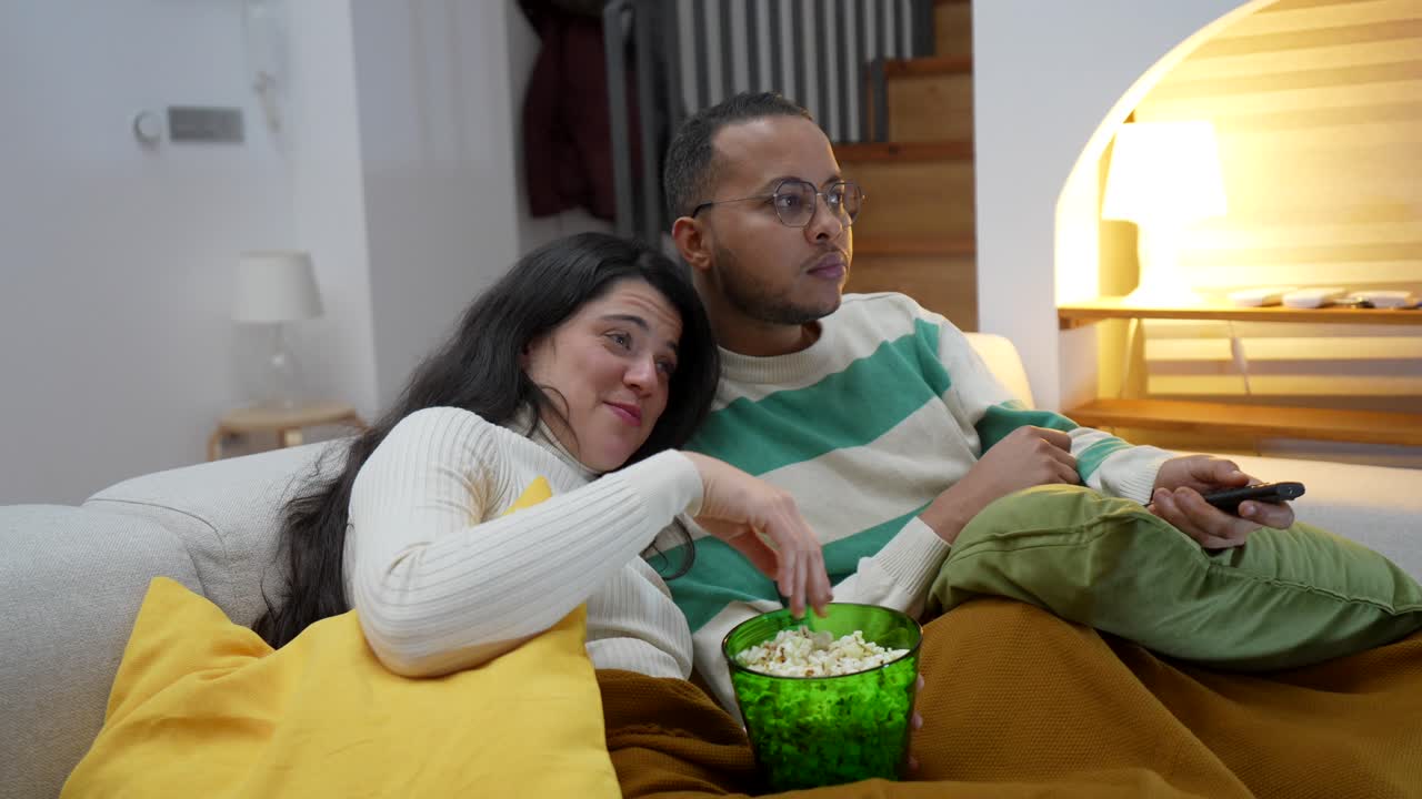 Par ser tv og spiser popcorn i sofaen derhjemme