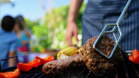 sección media del hombre volviendo la carne en la barbacoa