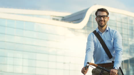 Handsome-man-in-business-style-riding-a-bicycle-and-stopping-in-front-of-the-camera