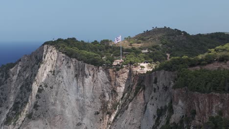 vista aérea de la bandera nacional griega ondeando en la cima de la colina por encima de los acantilados y el mar jónico, isla de zakynthos 50fps