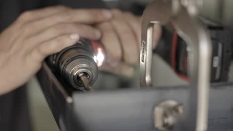 Drilling into metal construction corner slow motion close up shallow depth