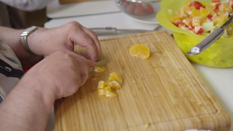 old woman cutting fruit for fruit salad