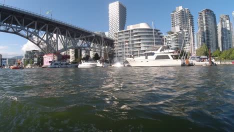 motor boating in false creek quayside under the granville bridge right by the yacht club at an epic achitectural marvel of modern condominiums vip luxury futuristic residential vancouver housing sunny
