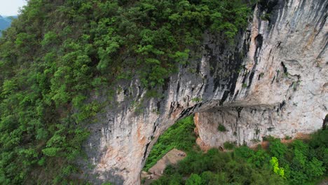 Aerial-view-of-a-massive-natural-rock-arch-in-green-foliage