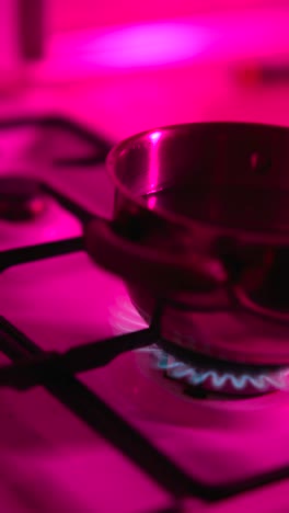 pink-lit gas stove with pot