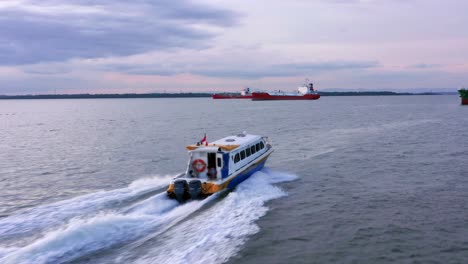 Tracking-Aerial-view-of-Passenger-boat-sailing-across-Balikpapan-Bay,-Oil-Tankers-in-the-background---East-Kalimantan,-Indonesia