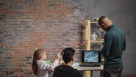 Girl-scans-father-hair-with-black-biology-teacher-in-lab