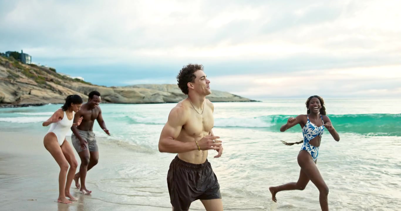 Gruppo di amici di diverse etnie che corrono e giocano sulla spiaggia