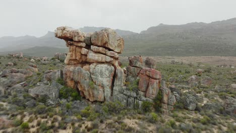 el dron vuela rápidamente sobre las rocas hacia la formación de rocas en el paisaje desértico del área silvestre de cederberg en sudáfrica - se pueden ver montañas en el fondo
