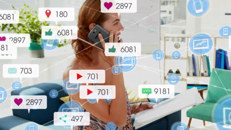 Animation-Von-Symbolen-Digitaler-Und-Sozialer-Medien-über-Einer-Kaukasischen-Frau,-Die-Im-Büro-Auf-Dem-Smartphone-Spricht