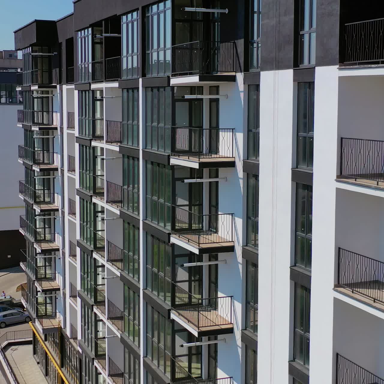 New architecture in the city. High-raise apartment buildings near the road. Modern design of multistorey building. Drone flight.