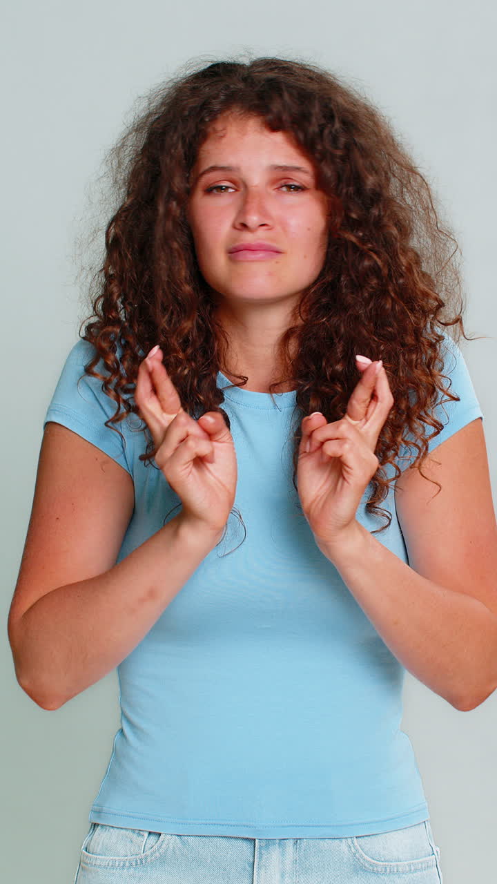 Young woman smiling crossing fingers hoping good luck wish positive optimistic anticipation gesture