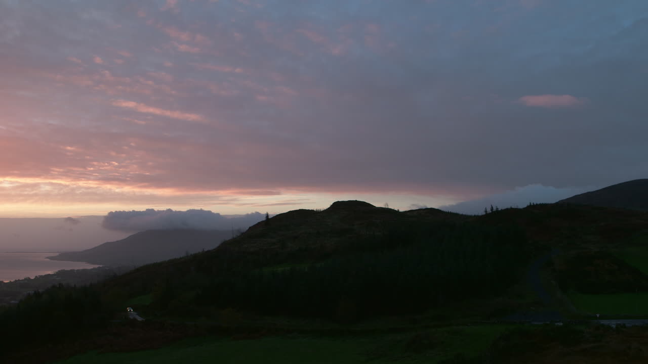 amanecer azul y rosa, nubes al atardecer, con montañas y mar