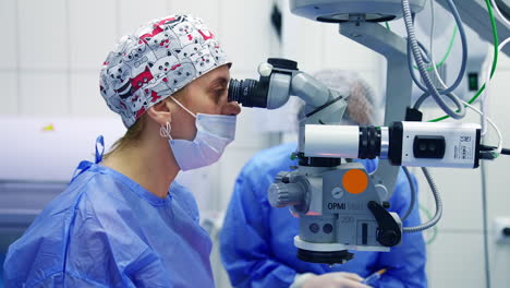 doctor using microscope for work. surgeon looking into the microscope at the eye of patient at the operating room