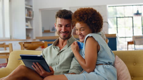 couple at home with digital tablet making purchase or booking using credit card
