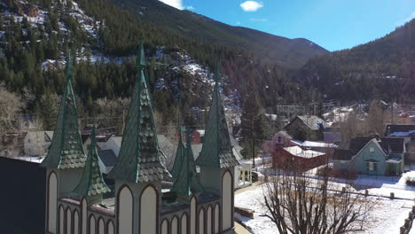 gothic church in the foreground in breckenridge town, colorado filled with snow - drone shot