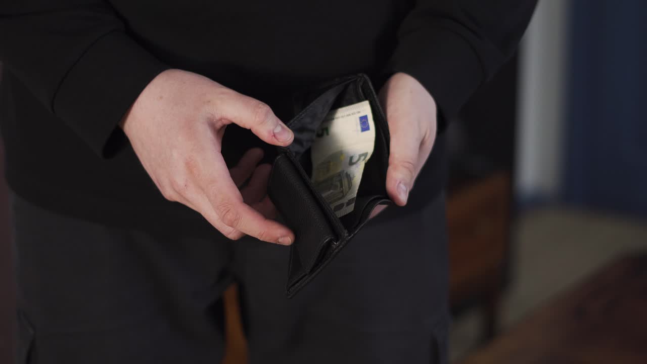 Close-up of hands opening an almost empty wallet with a few banknotes, showing money shortage, financial struggle, and poverty concept
