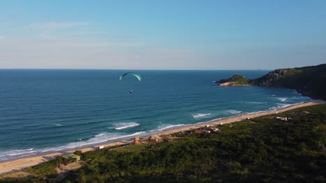 paraglider flying over the tropical beach on  sunny summer day, drone view