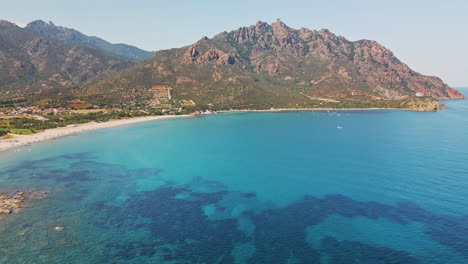 stunning sardinian maritime landscape with clear blue sea and long beach with mountains in the background on a sunny day in sardinia, italy - aerial drone shot