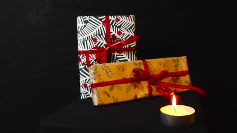 imágenes de zoom en regalos de navidad y regalos con papel de embalaje de vacaciones y cintas rojas en un fondo negro oscuro. una vela está ardiendo delante de ellos creando una luz cálida y sombras