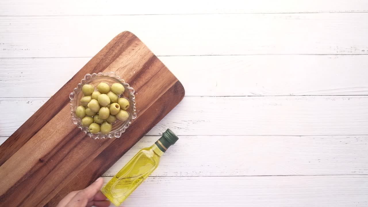 зеленые оливки на деревянной доске для резки с оливковым маслом