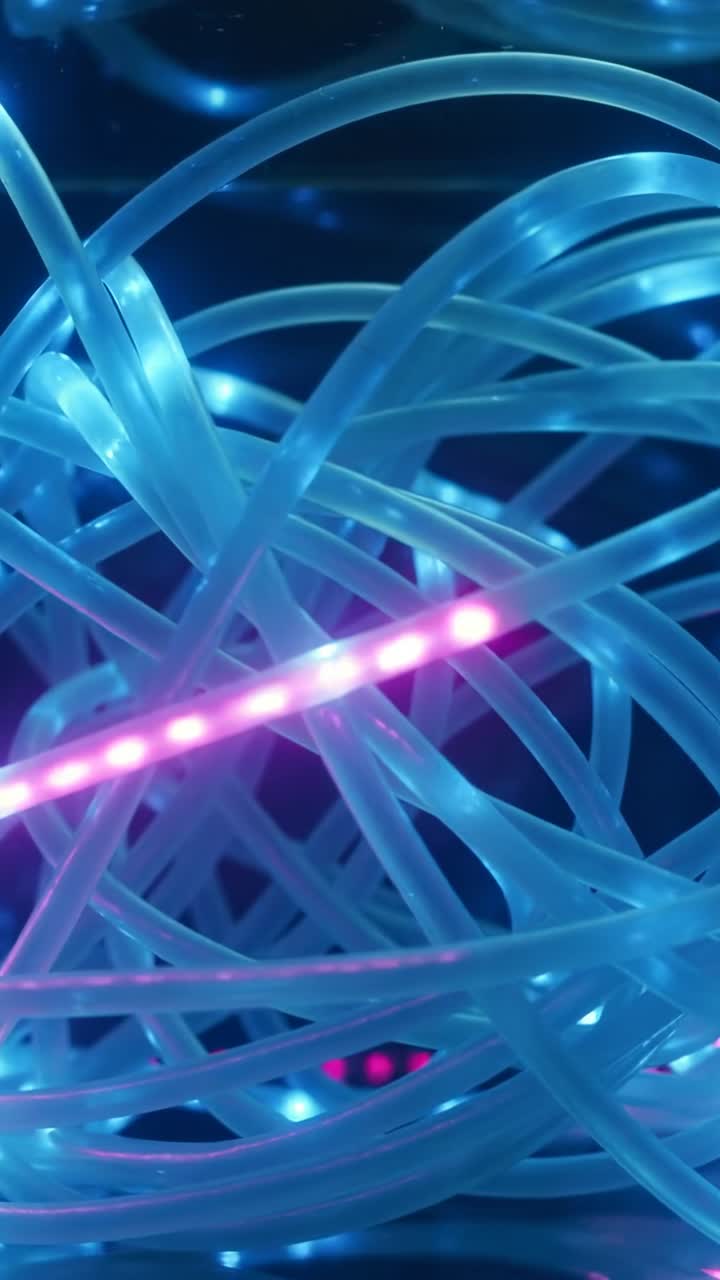 Vertikal video: Glidende magenta LED-stang krydser blå fiberstråde i et mørkt sæt, skaber lyserøde glimt