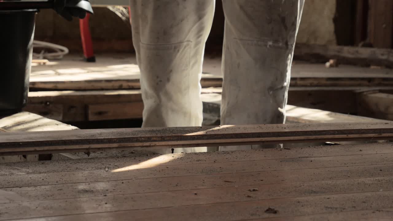 Man using crowbar to tear out old boards from old house