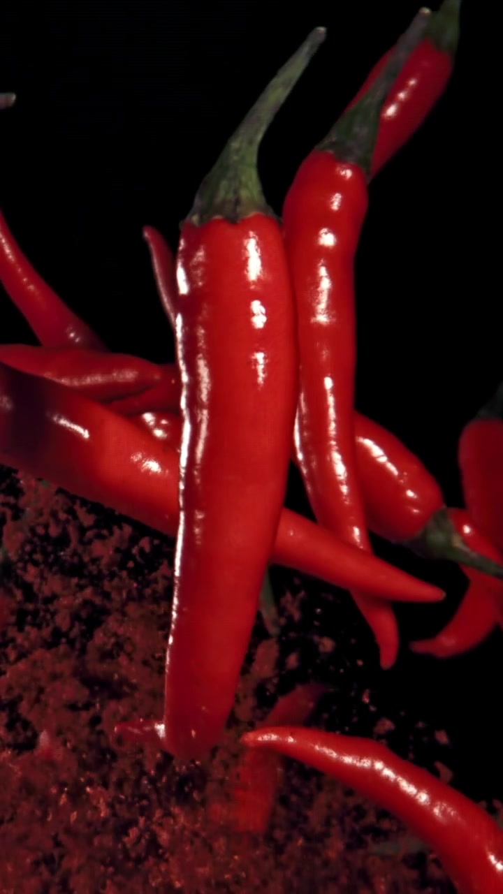 Vibrant Red Chili Peppers and Powder Falling in Slow Motion