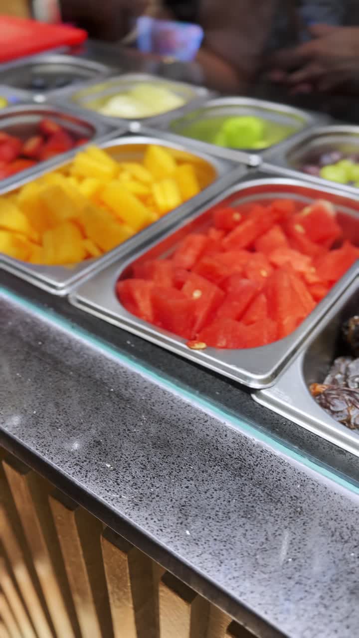 A fruit display with a person wearing gloves