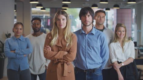 portrait of couple leading multi-cultural business team standing in modern open plan office