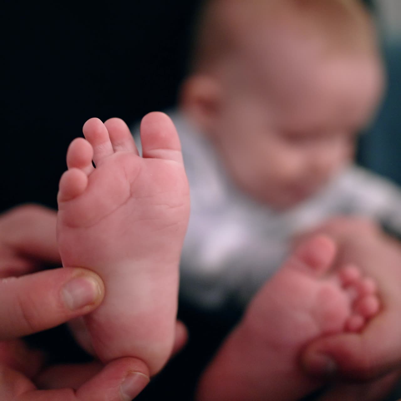 Father's hands hold the tiny bare feet of his son. Little baby boy in dad's arms. Close up