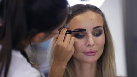 makeup artist combing eyebrows with a brush