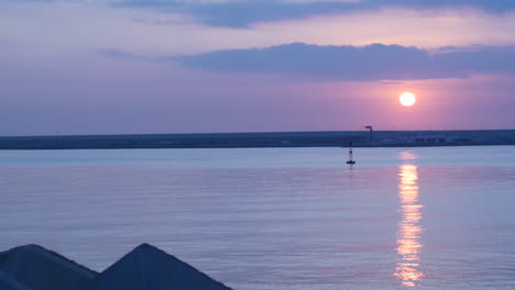 purple and pink sunset over calm sea with buoy