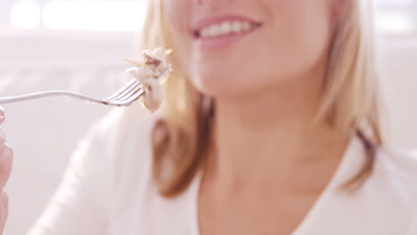 mujer rubia comiendo pollo en un sofá