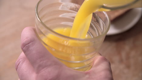 slow motion shot of pouring orange juice into glass from jug