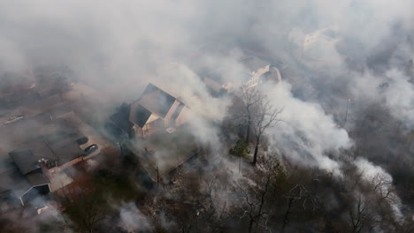 close up aerial footage of houses that are covered in smoke from a wildfire that is very close to the neighborhood.