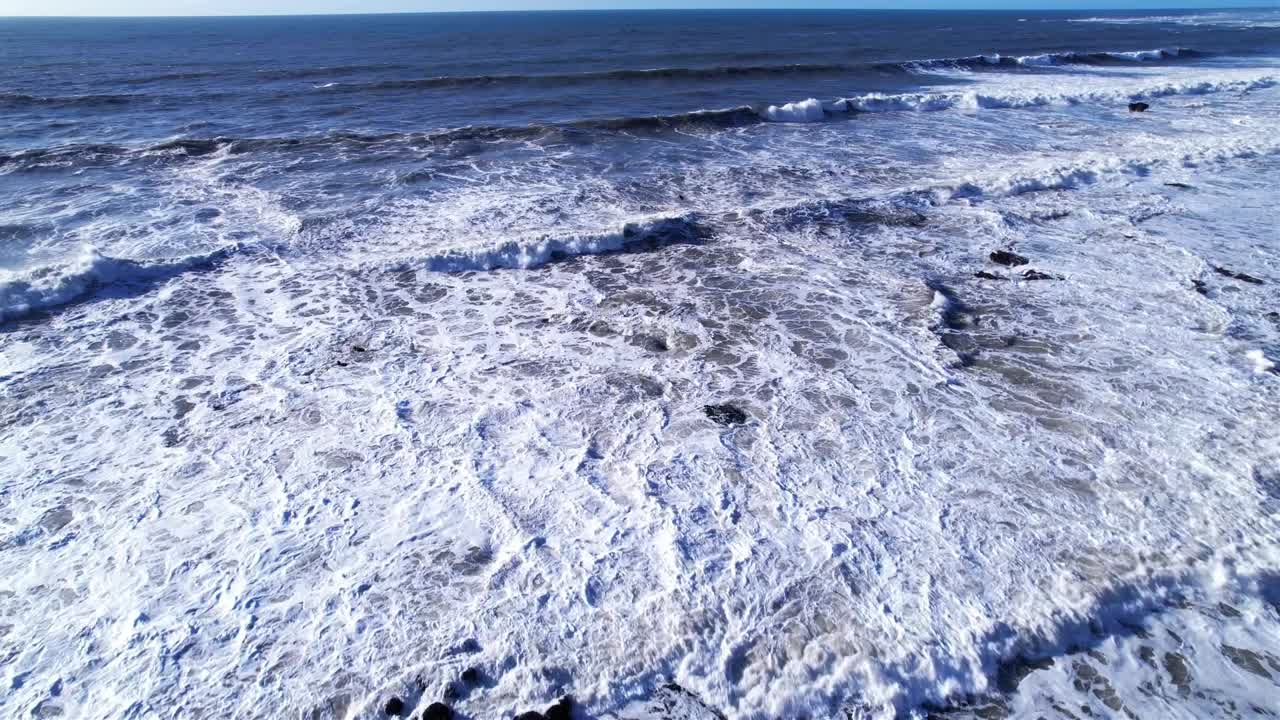 drone vuela sobre la marea entrante en mavericks beach, california durante la puesta de sol