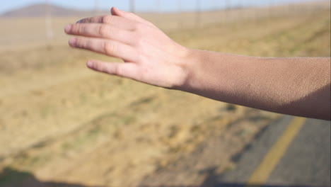 Hermosa-Chica-Rubia-Sosteniendo-El-Brazo-Fuera-De-La-Ventana-Del-Auto-Disfrutando-De-Un-Viaje-Por-Carretera-En-Un-Auto-Convertible-Vintage