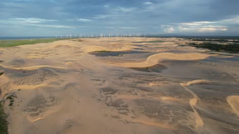 Hermosa-Toma-De-Dunas-Con-Drones-En-El-Noreste-De-Brasil-Al-Atardecer,-Luz-Mágica-Y-Turbinas-Eólicas-Al-Fondo