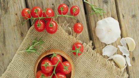 video de tomates de cereza frescos en un cuenco y ajo en un paño rústico sobre un fondo de madera