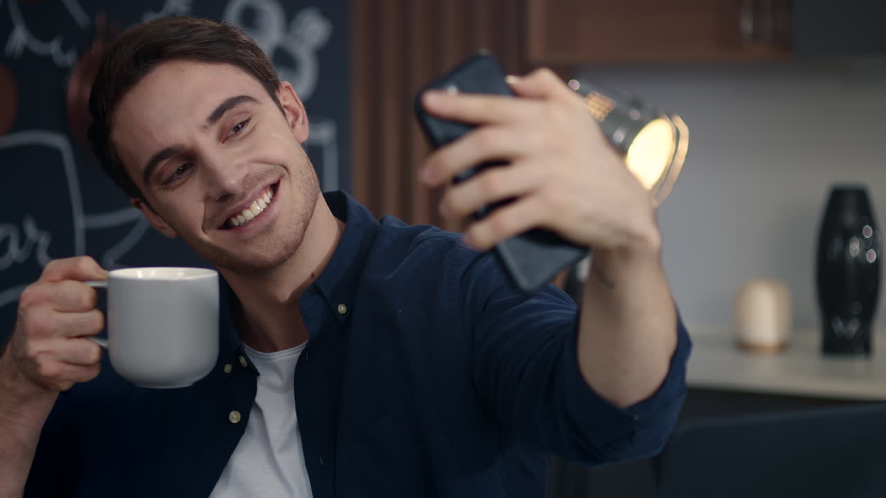 hombre sonriente haciendo una foto de selfie en el teléfono móvil en la oficina de casa. hombre haciendo caras