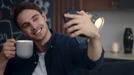 smiling man making selfie photo on mobile phone at home office. guy making faces