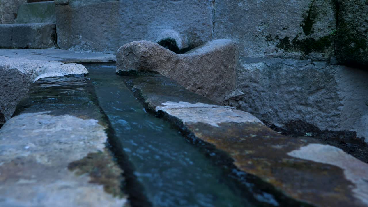 Boiling hot water pours along open shallow granite rock trench in Ourense Spain