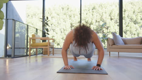 exercising on yoga mat, plus size woman doing push-ups in modern living room