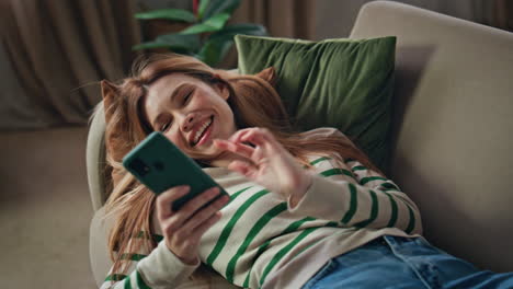 woman making cellphone selfie lying home couch closeup. girl taking picture face