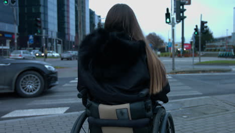 Back-view-of-woman-in-wheelchair-is-waiting-for-green-light-on-pedestrian-crossing,-crosswalk