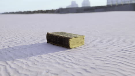 old book resting on the smooth sands near a quiet shoreline at sunset